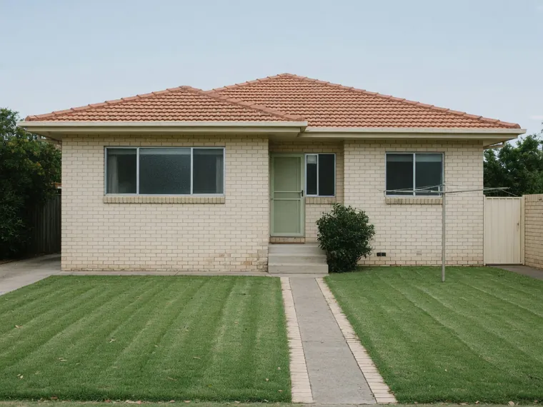 A plain 1960s cream brick house with aluminium windows and a low pitched roof.
